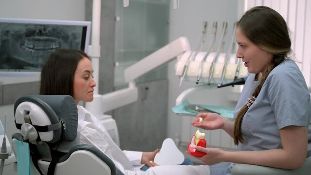 Dentist with a patient looking at a tomographic image of the teeth and discussing a treatment and implantation plan