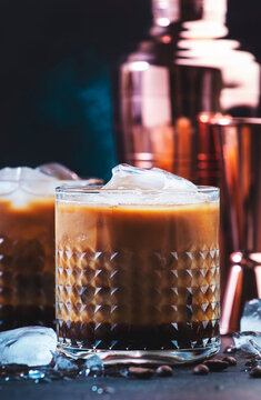 Trendy alcoholic cocktail drink with vodka, coffee liqueur, cream and ice on dark background,  copper bar tools. Negative space