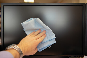 Cleaning the surface of the monitor and TV screen from dirt and dust with a napkin.