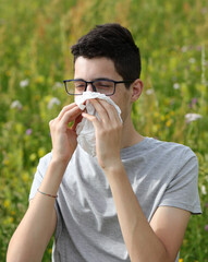 allergic boy with glasses sneezing on a white handkerchief