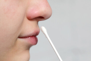 Obraz premium swab to carry out a test and rapid for the search for coronavirus in the nose of the young girl