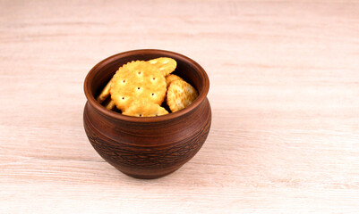 Round cookies in a clay pot on a wooden background