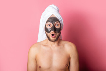 surprised bearded young man with cosmetic mask on his face background. Care, cleaning