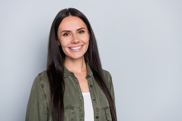 Portrait of attractive cheerful long-haired woman wearing khaki shirt isolated over grey pastel...
