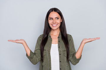 Portrait of attractive cheerful long-haired woman holding copy space on palms ad isolated over grey...
