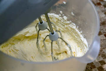 The process of whipping cream with mixer. Close-up. Selective focus. Picture for articles about food, confectionery, recipes.