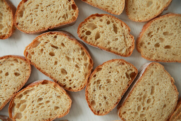 Bread and pastries. Pattern of slices of white ciabatta bread on a white wooden background. Background image, copy space. Top view, flatlay