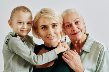 Minimal close up portrait of three women in family smiling at camera in studio