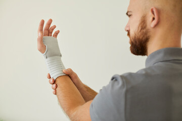 Man uses orthopedic medical bandage for wrist as preventive measure for sports or physical...