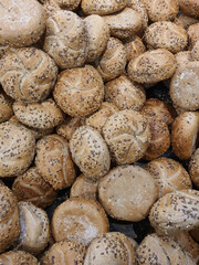 Freshly baked round bread rolls or Kaiser rolls, buns with sesame, flax seeds and linseeds in a bakery or grocery store