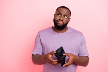 Photo of suspicious unsure young guy wear purple t-shirt thinking how earn money isolated pink color background