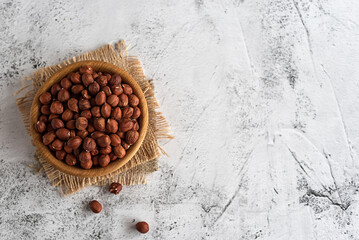 Wooden bowl with hazelnuts on a gray marble table.