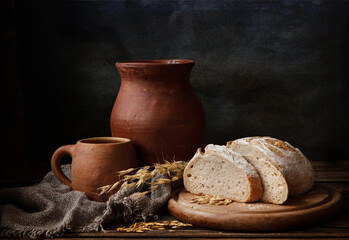 Homemade bread and vintage ceramic kitchenware on an old wooden table. Artistic Still Life in...