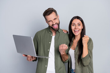 Photo of ecstatic guy lady married spouses fists up web bargain notification use netbook isolated over grey color background