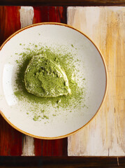 Vegan tiramisu with matcha tea with strawberries on a plate on a wooden background. Diet dessert. Serving in a restaurant. Copy space, close up. The concept of healthy eating.