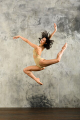 Fototapeta na wymiar Flexible woman performing jump in studio