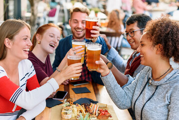 Cheerful diverse friends clinking beer glasses