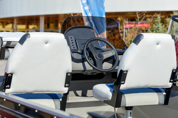 The steering wheel and white leather seats of a riverboat.