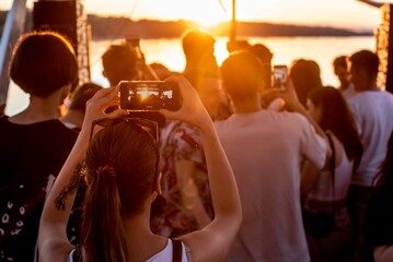 sunset and a girl filming on her phone