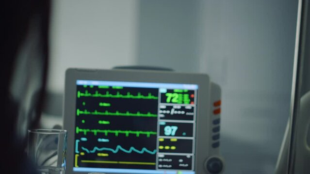 Woman holding patient hand in ward closeup. Hospital heartbeat computer screen.
