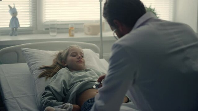 Doctor Examining Ill Girl Symptoms With Stethoscope In Pediatric Unit Ward.