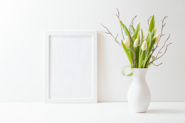 Home interior with decor elements. Mockup with a white frame and white tulips in a vase on a light background