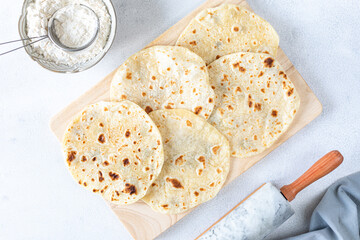 Homemade wheat tortillas, pita bread, tortilla, pita with ingredients for cooking on a white table....