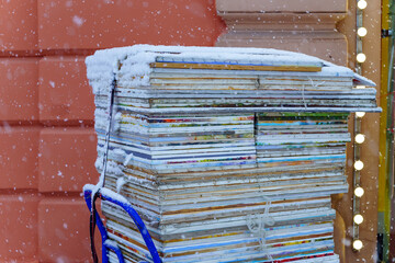 Hostas with paintings lie in a stack in a cart under the snow