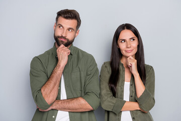 Photo of young married couple hand touch chin thoughtful dreamy look empty space isolated over grey...