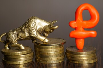 A metal bull figurine and a ruble symbol with coins. Economics and finance.