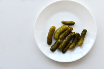 Green pickles on a white plate and a fork