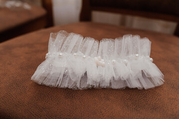 White garter of the bride on a brown background. Wedding