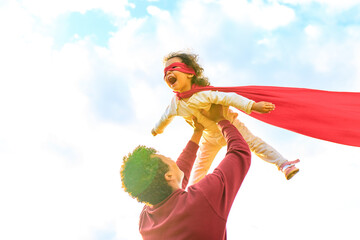 happy african american little fearless girl flying outdoor on father's hands in summer park