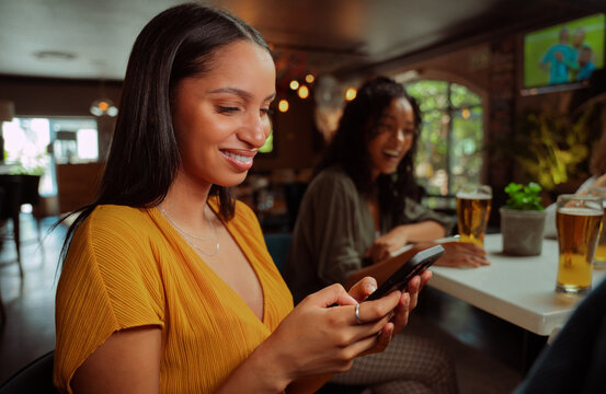 african american female out for drinks texting on mobile phone 