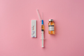 Positive medical test for covid-19 and vaccine with a syringe for coronavirus on a pink isolated background. The concept of testing and protecting people. Copy space, top view