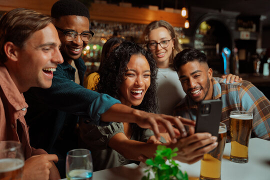 Group of young adult friends taking selfies at dinner sitting in restaurant 