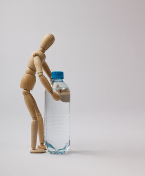 wooden mannequin raises a water bottle on a white background