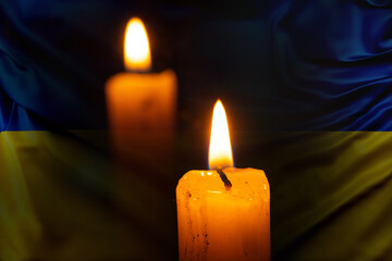 The flame of a candle against the background of the flag of Ukraine is yellow-blue, we mourn for those who died in Ukraine, mourn