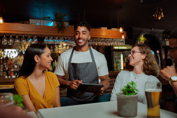 African american waiter serving customers in restaurant