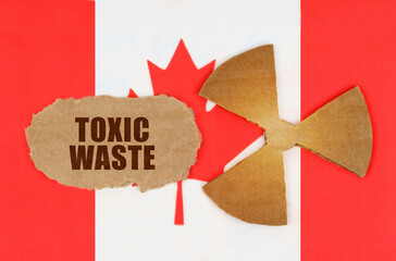 On the flag of Canada, the symbol of radioactivity and torn cardboard with the inscription - Toxic...