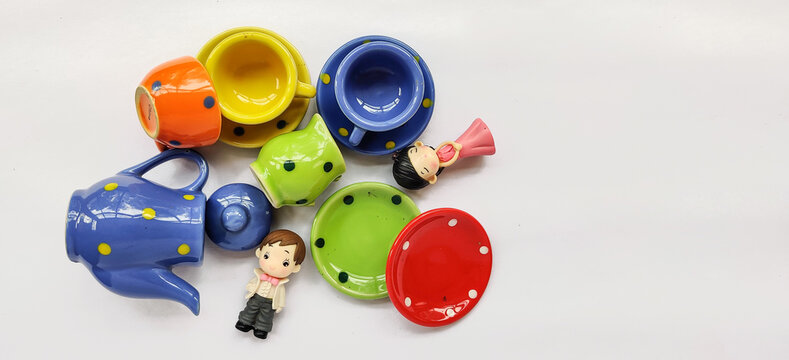 Miniature Boy and Girl with Tea, Coffee Cup and Saucer set scattered on Table. Flatlay Photography. Colourful playset, Flat overlay photography.
