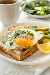 French breakfast with croque madame sandwich close-up on the white plate.
