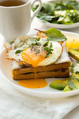 French breakfast with croque madame sandwich close-up on the white plate.