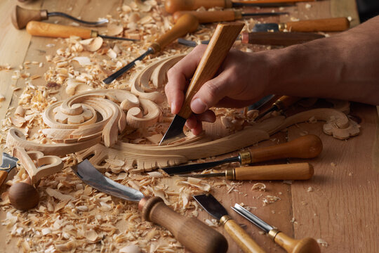 Woodwork and Wood carving. Carpenter's hands use chiesel. Senior wood carving professional during work. Man working with woodcarving instruments