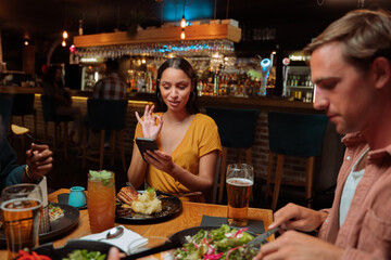friends out for dinner women taking pictures of meal and drink