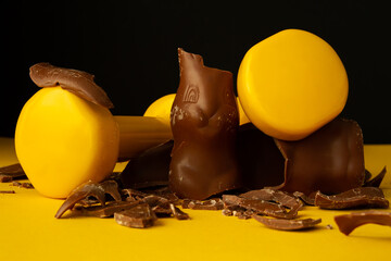 Heavy dumbbells crushing Easter chocolate bunny candy. Healthy fitness lifestyle composition, gym...