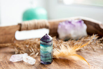 Translucent Fluorite crystal standing point gemstone in home bed room on natural wood tray. Healing and clearing energy concept. - obrazy, fototapety, plakaty