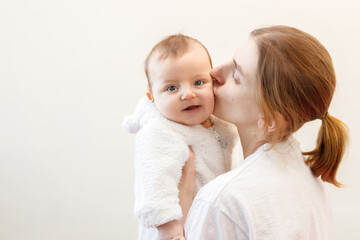 the mother kisses the baby on a light background. protection