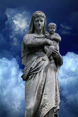 Fototapeta na wymiar Queen of Heaven. Virgin Mary with baby Jesus Christ. An ancient statue against blue sky background.