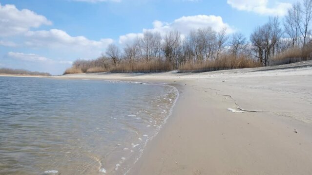 Winter landscape. An empty beach on the eve of spring. Waves on the water and cold sand. It's springtime, snow and ice are melting. The nature of the left bank of the Don River. Stanitsa Romanovskaya.